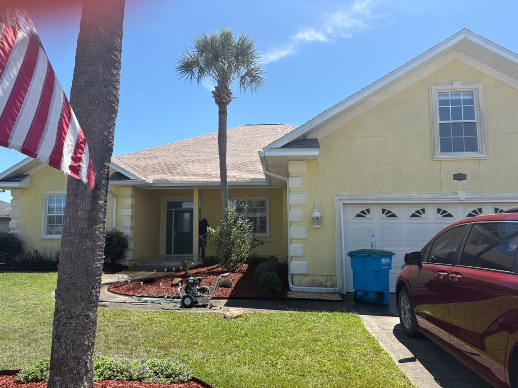 Stucco home exterior before — surfaces being pressure washed and prepped